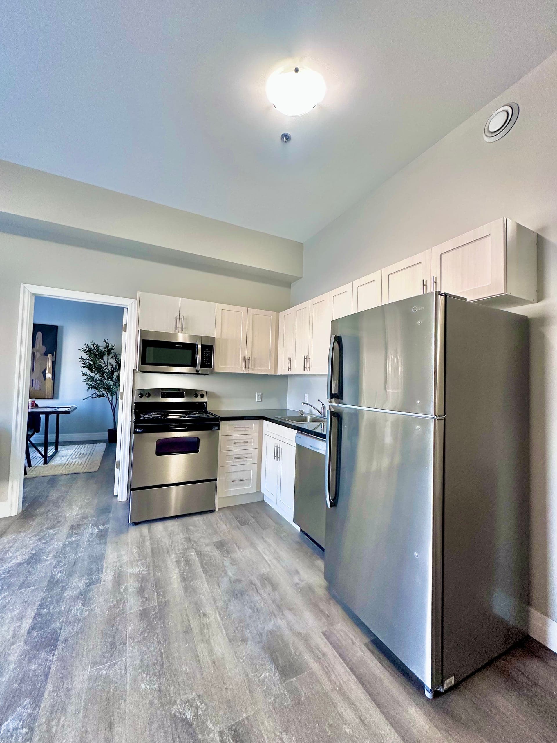 Suite kitchen with stainless appliances and a dishwasher, open to the living room